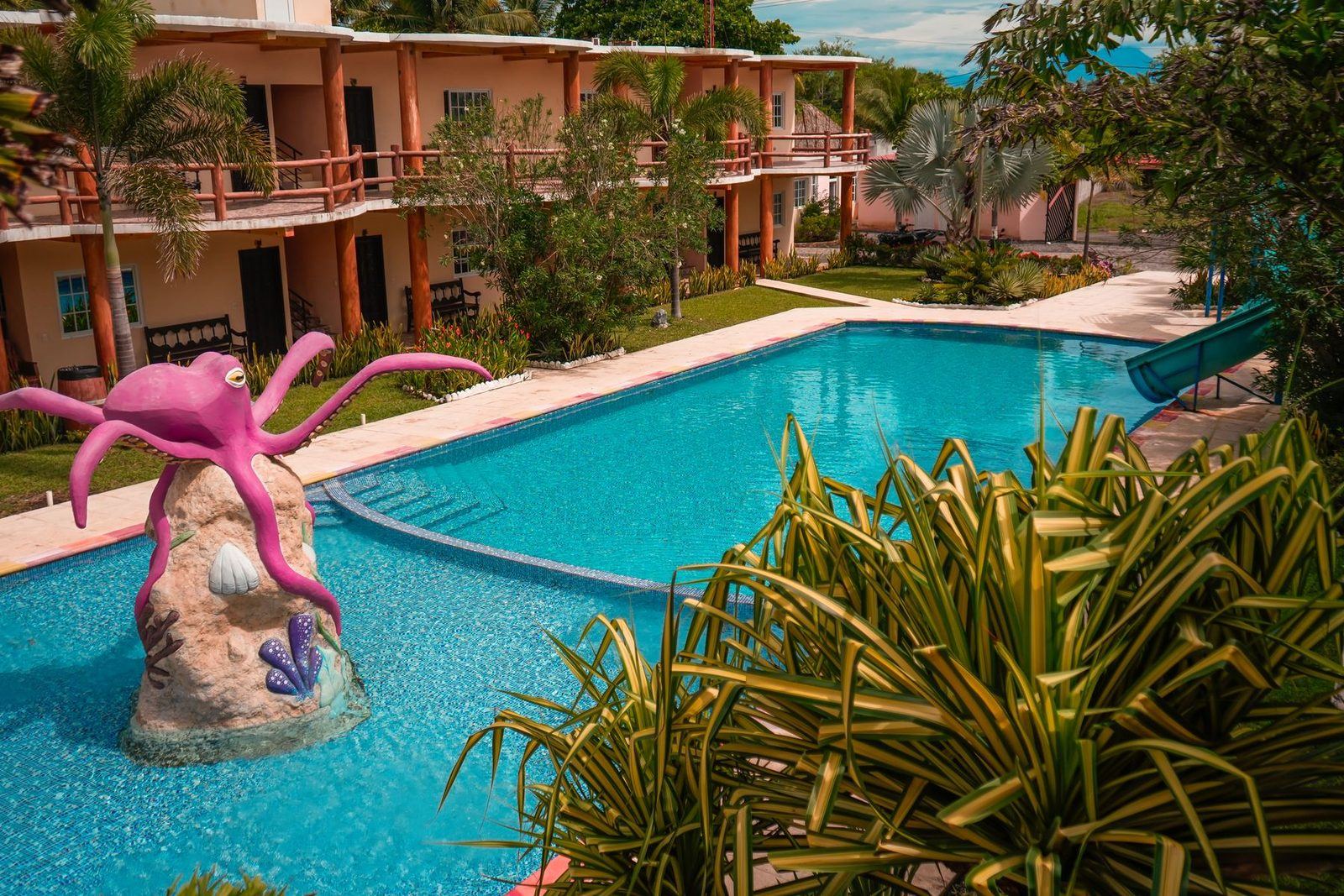Jardines y piscinas del hotel entre palmeras bajo el cielo del Pacífico.