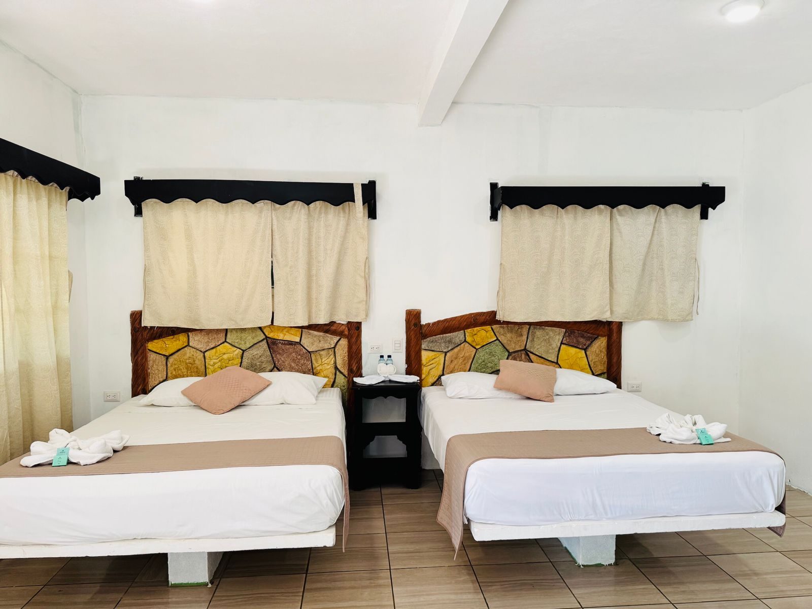 Habitación del hotel con dos camas, cabeceras de madera y ropa de cama blanca.
