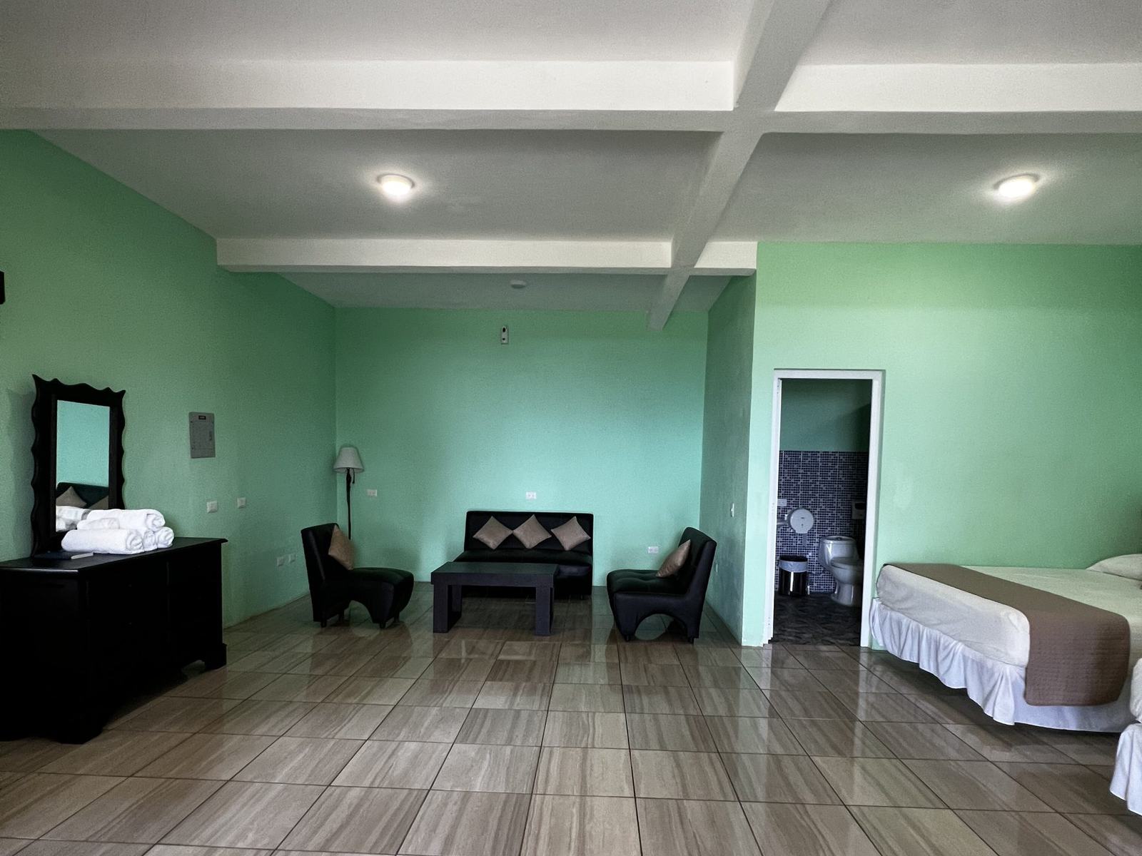 Habitación amplia del hotel con camas, cómoda de madera y una pequeña sala de estar.