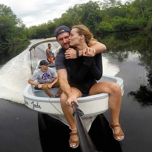 Personas a bordo de una lancha avanzando por un canal estrecho rodeado de vegetación verde.